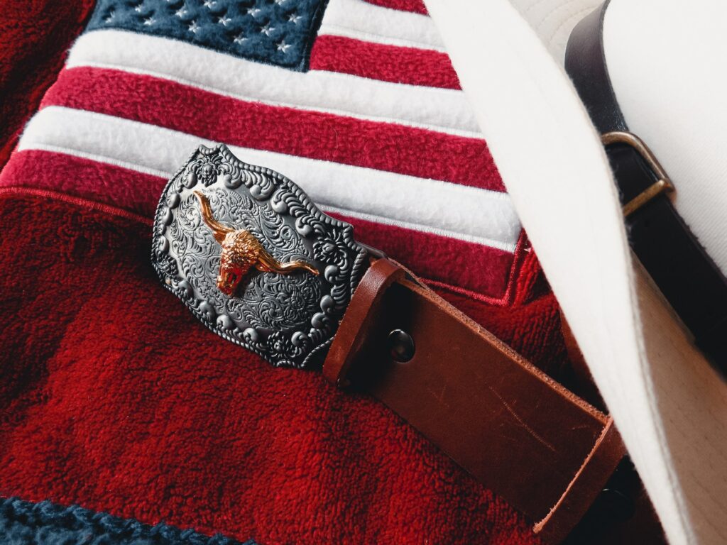 A Texas style cowboy buckle with hat and American flag.