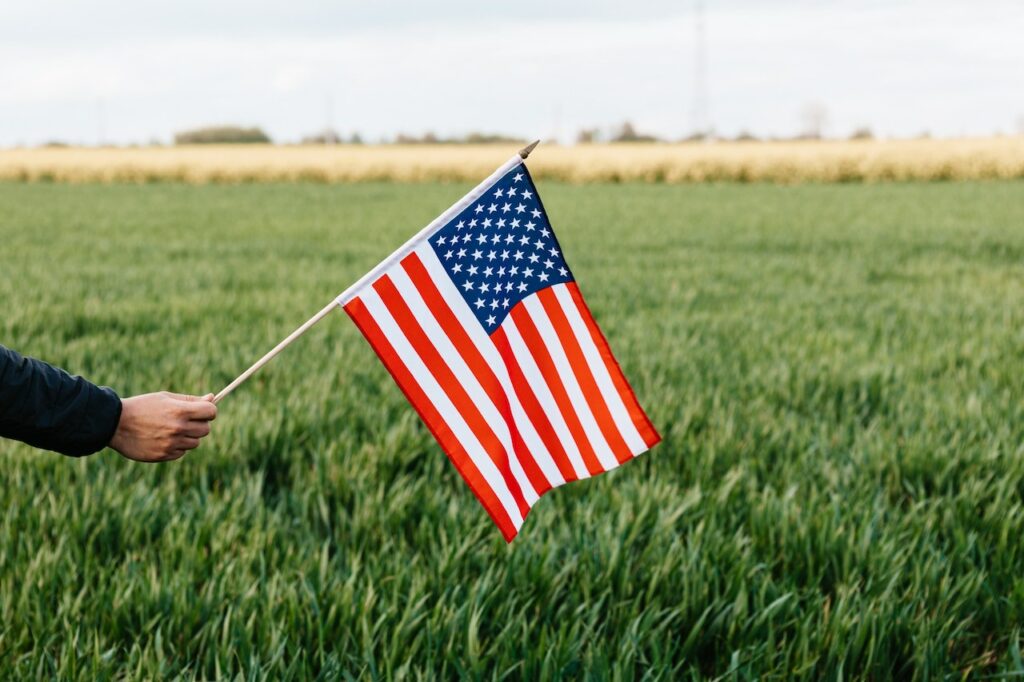 Crop faceless person showing American flag on field on Labor day