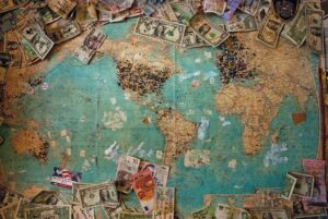 World map with pins and banknotes showing how does owning land make money