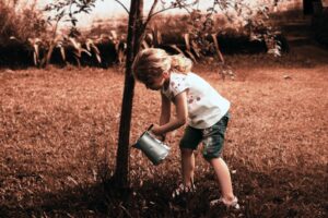Child girl watering tree while living frugal