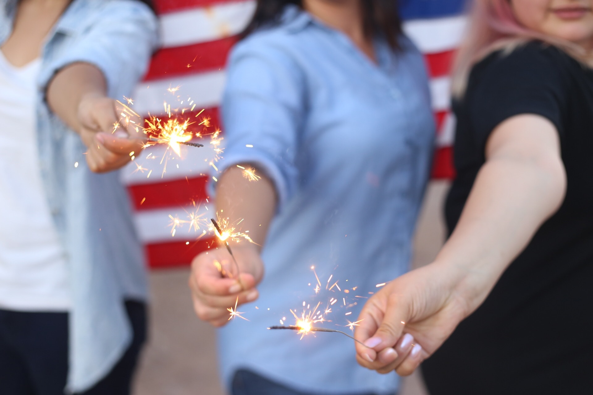 blurred silhouettes of women celebrating happy fourth of July with the American flag in the background 