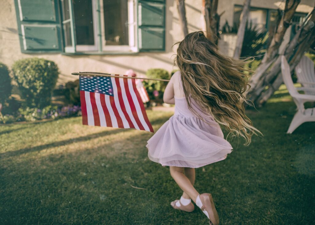 Girl running and waiving the American flag for a happy fourth of july