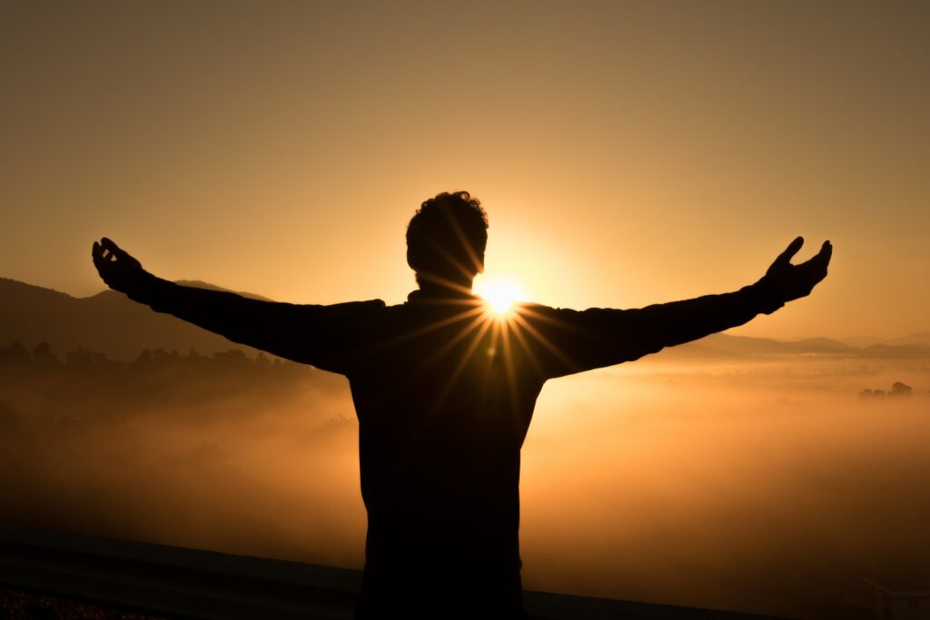 Man facing sunset with arms wide open