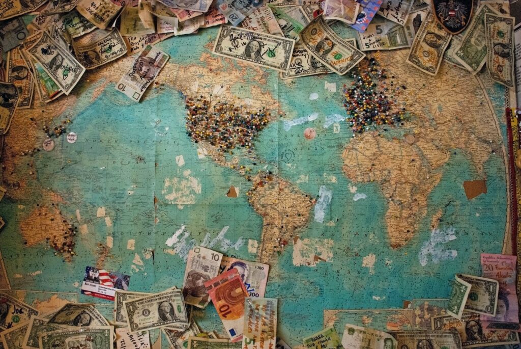 World map with pins and banknotes showing how does owning land make money